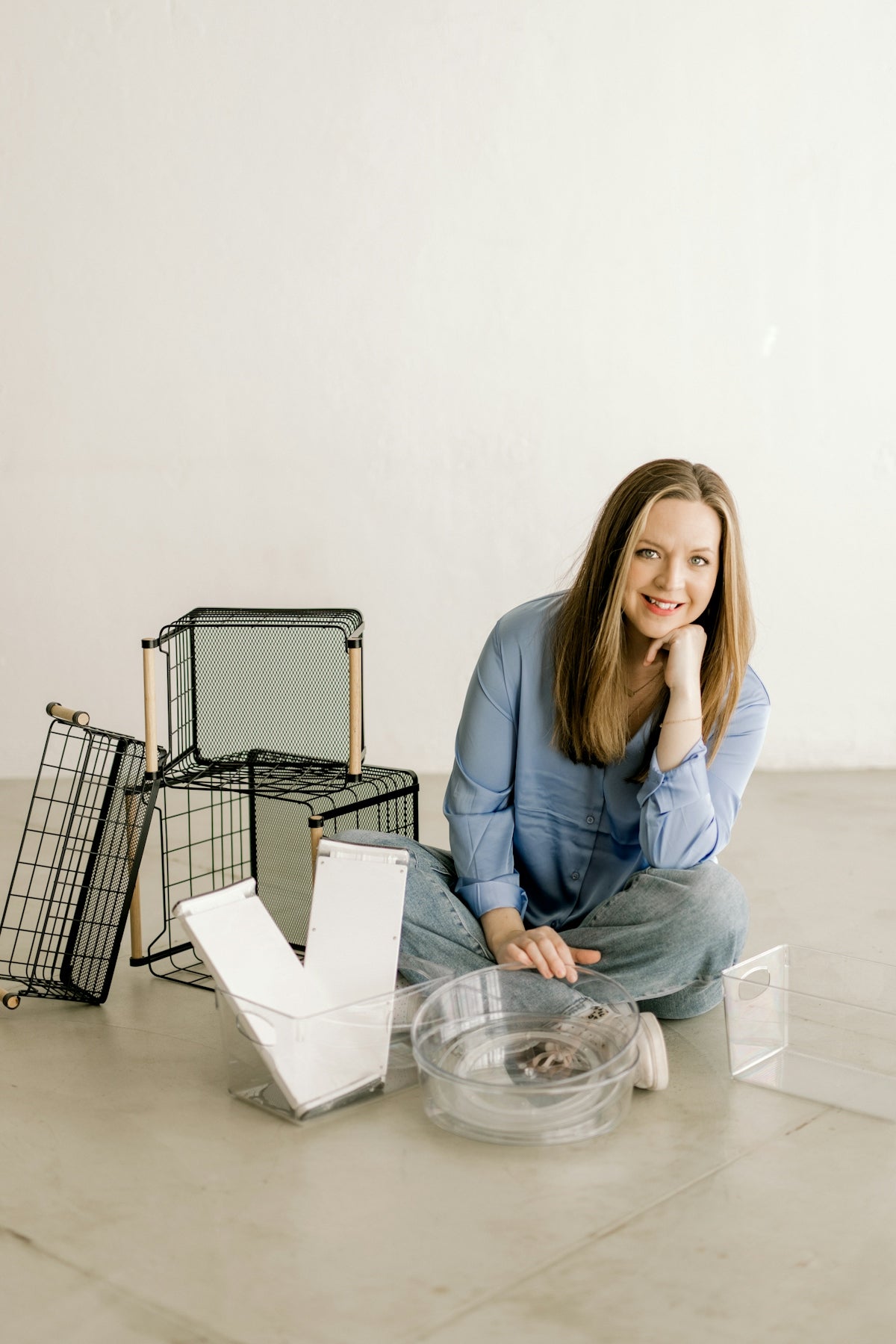 Smiling woman on floor surrounded by home organization products
