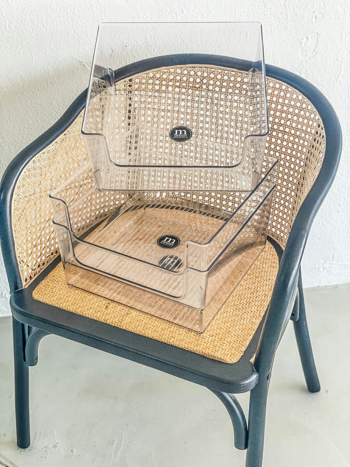 Two clear plastic organizers stacked on a cane chair