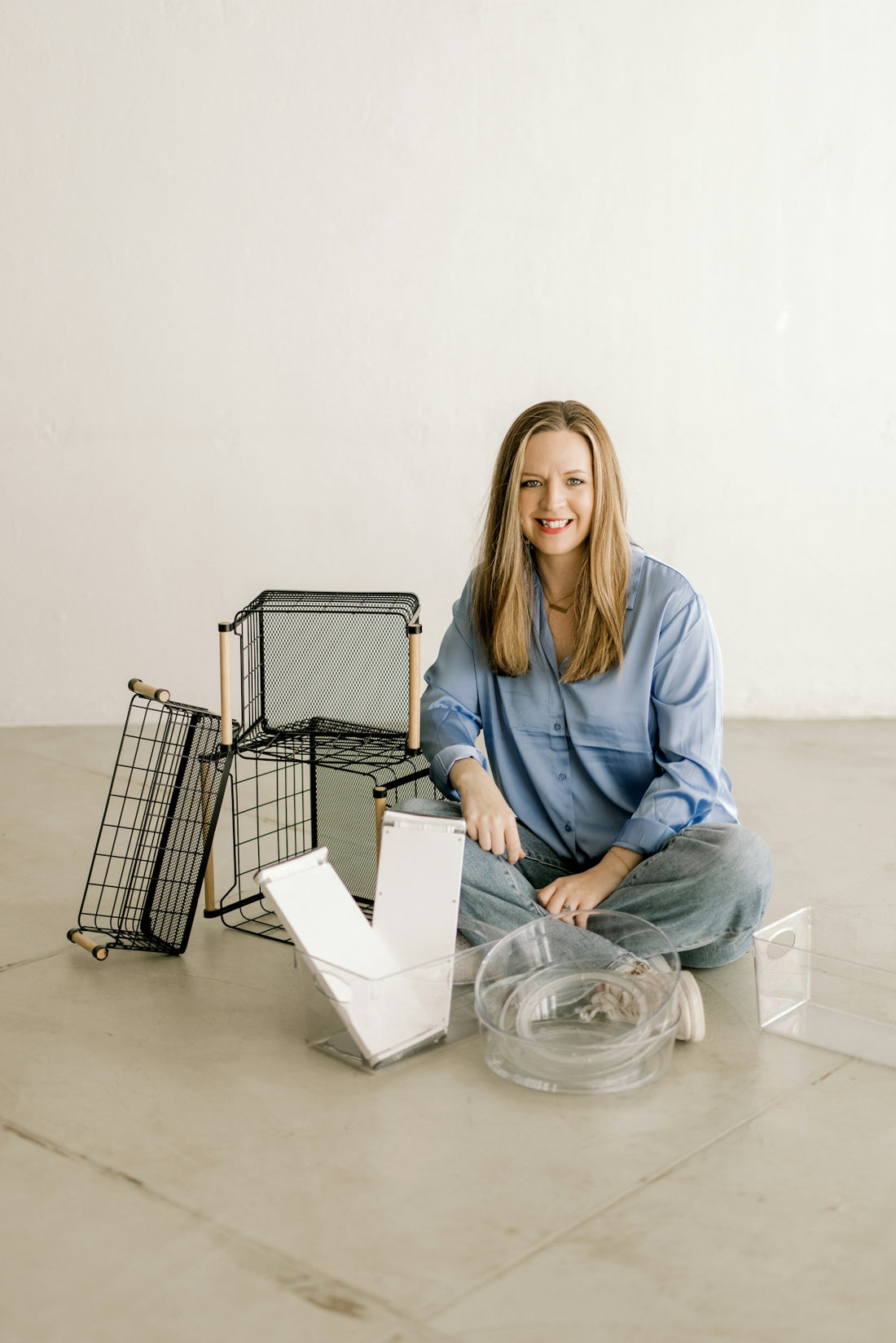 Smiling woman with organizational baskets and clear containers on floor
