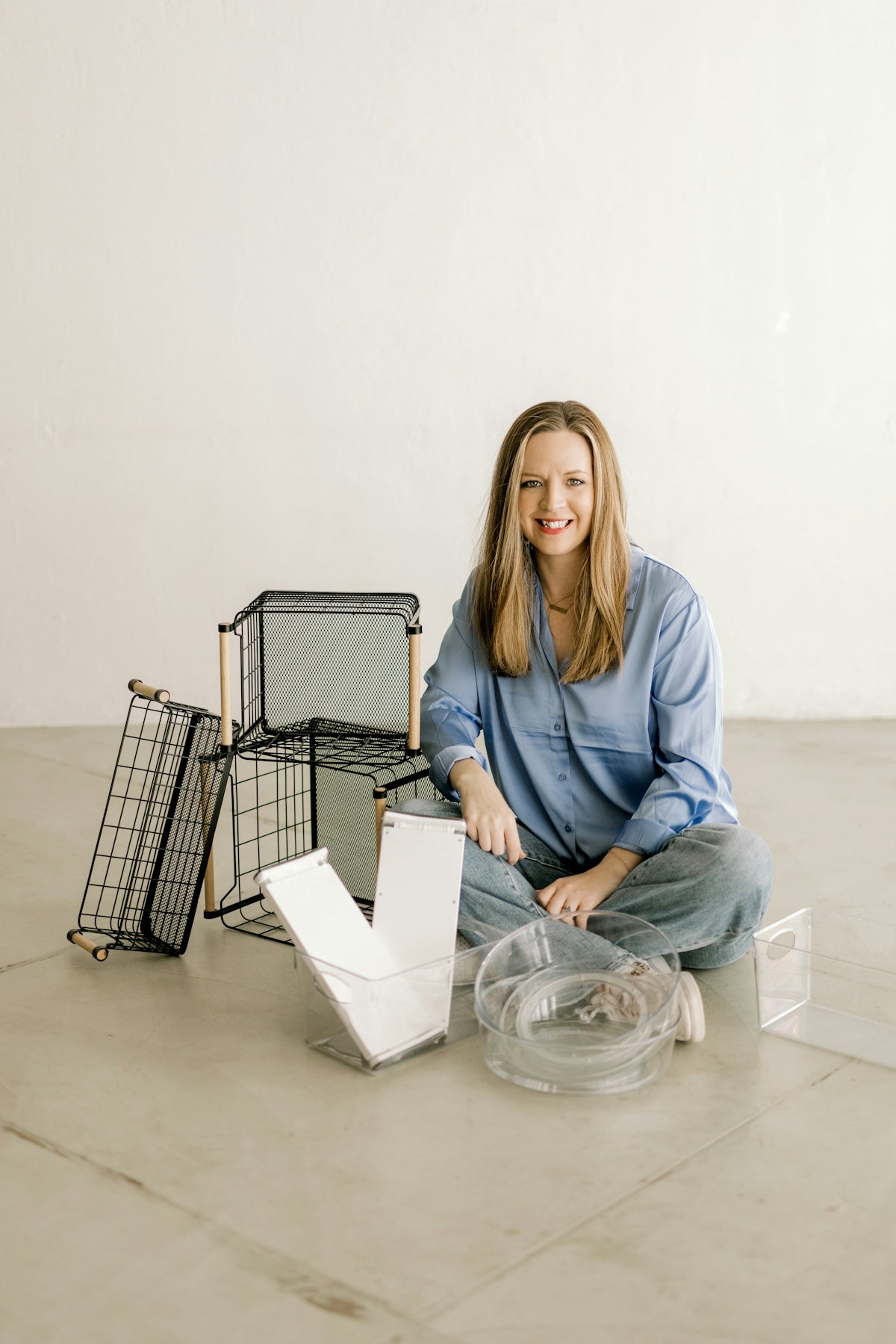 Smiling woman with organizational baskets and clear containers on floor