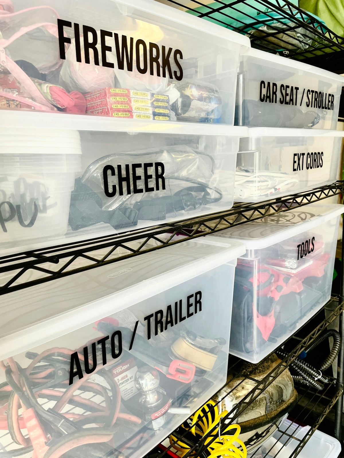Clear plastic storage bins with black labels on a metal wire shelving unit